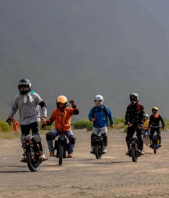 Five riders spread across the volcanic sand plain