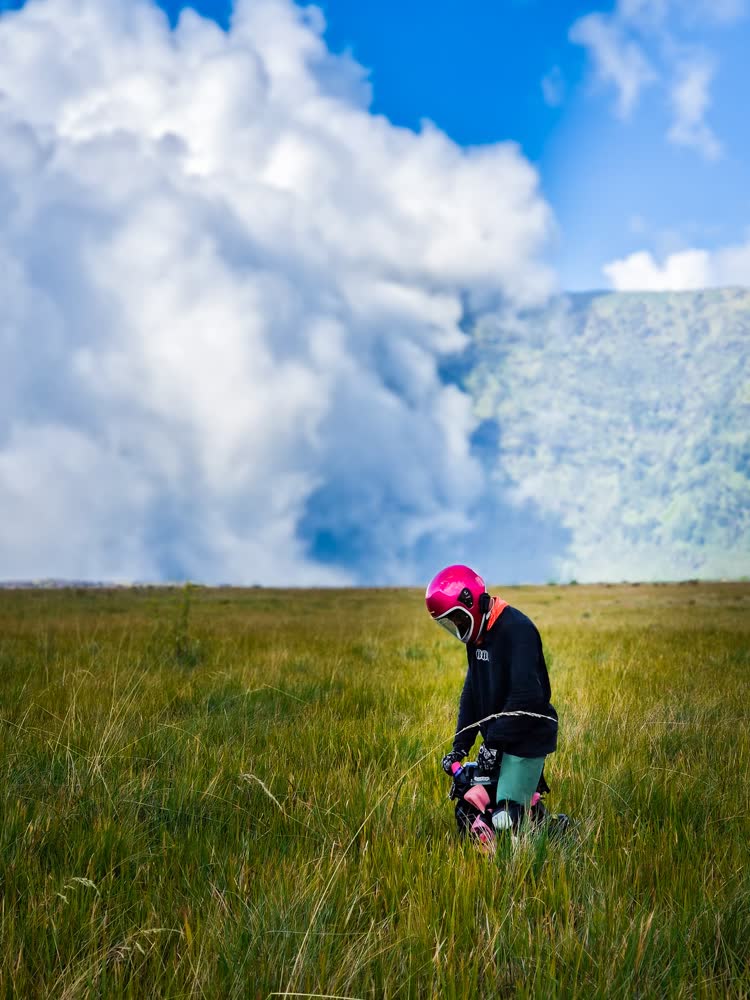 Cloud bank rolling over the Bromo caldera with a rider in the grass below
