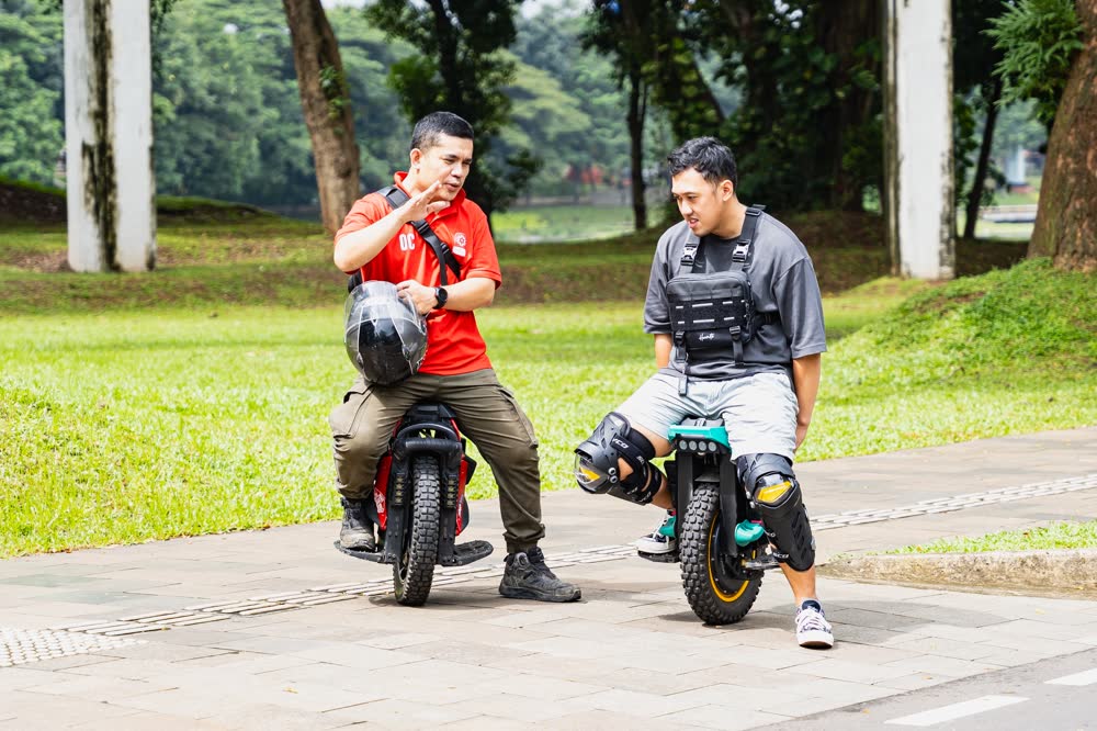 Two riders seated on their machines in the park