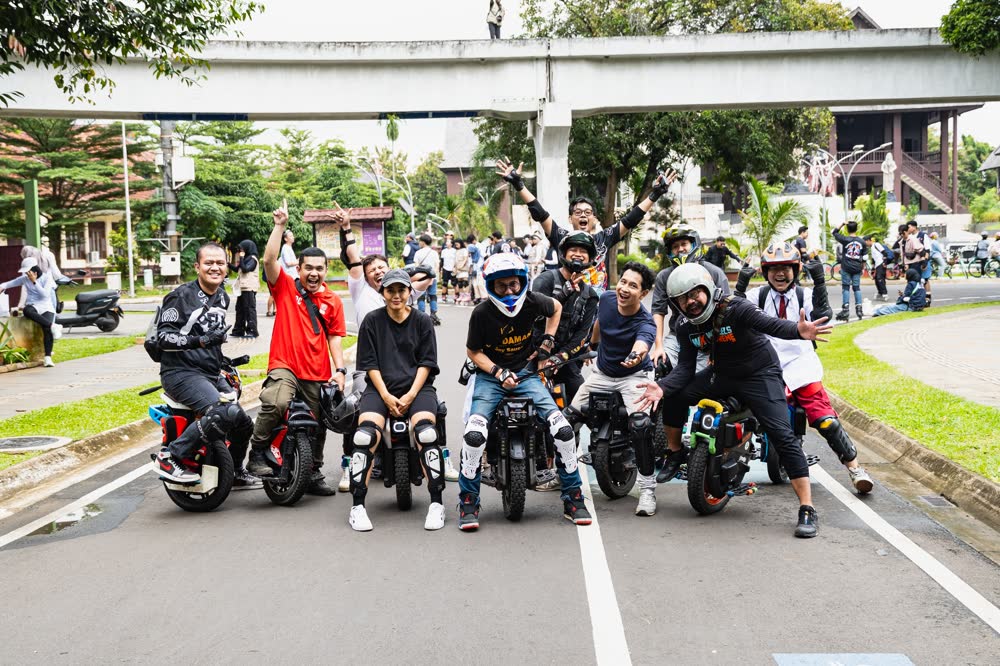 Large group of riders filling a closed road with arms raised