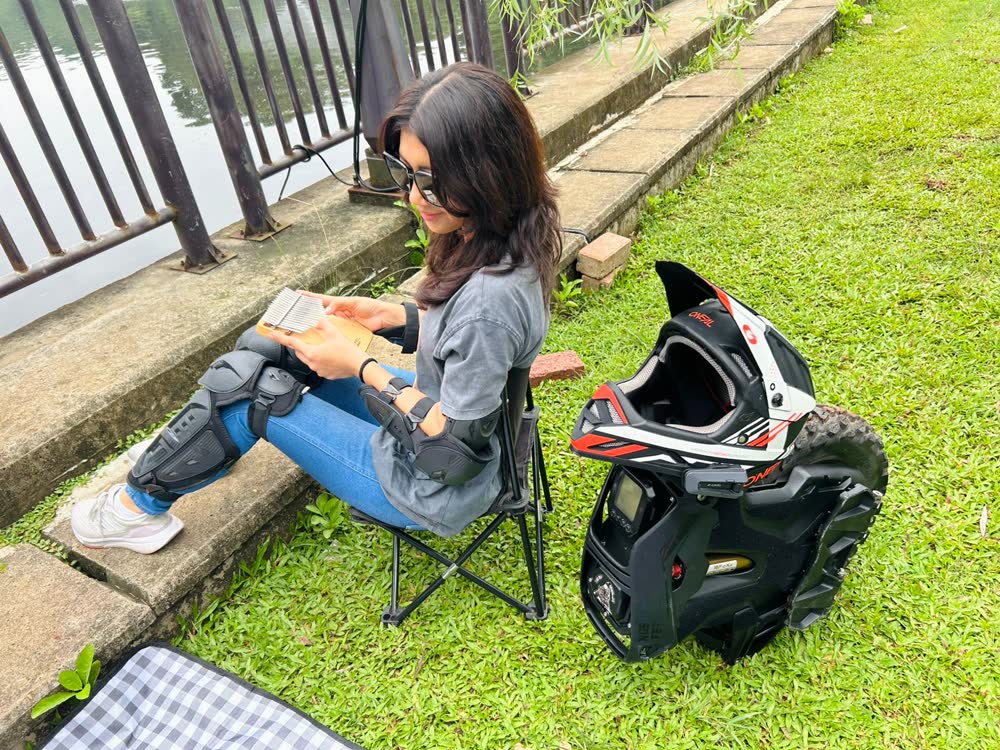 Rider sitting on a folding chair on the grass with helmet beside them