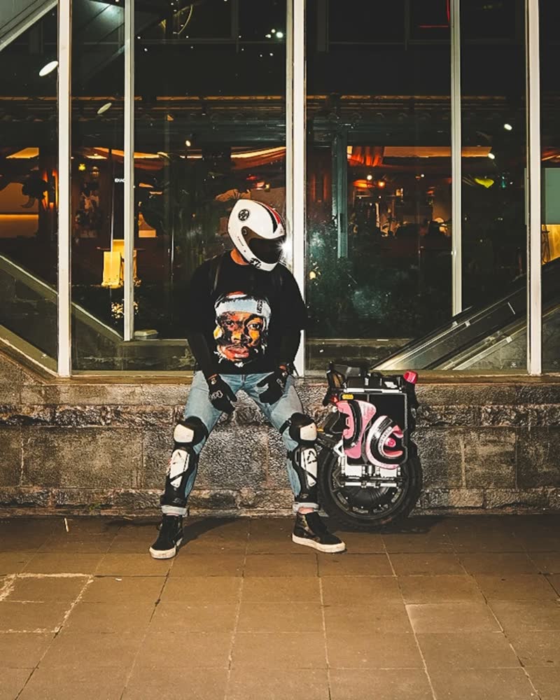Rider seated on a ledge outside a lit station at night