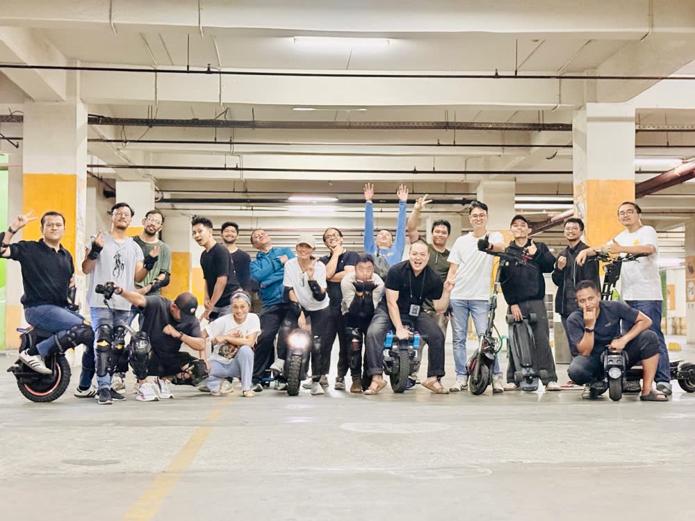 Large group of riders posed across a parking garage floor