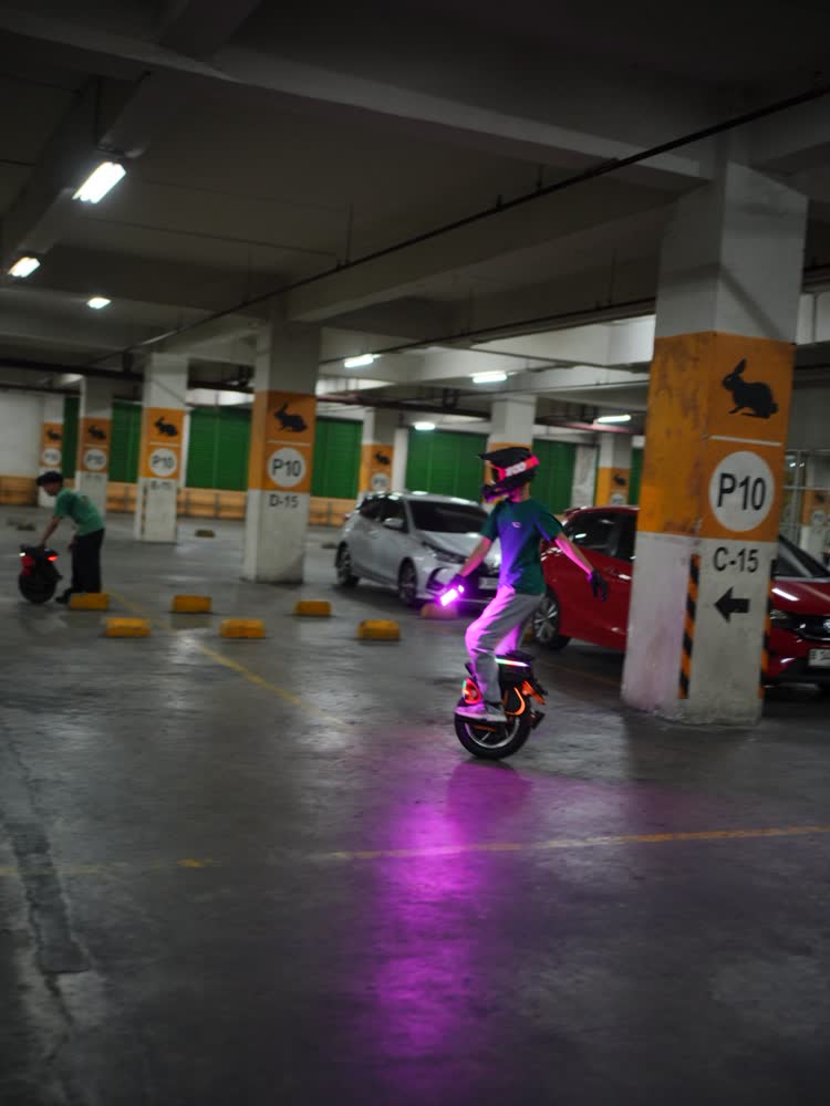 Rider with pink underglow riding between parked cars