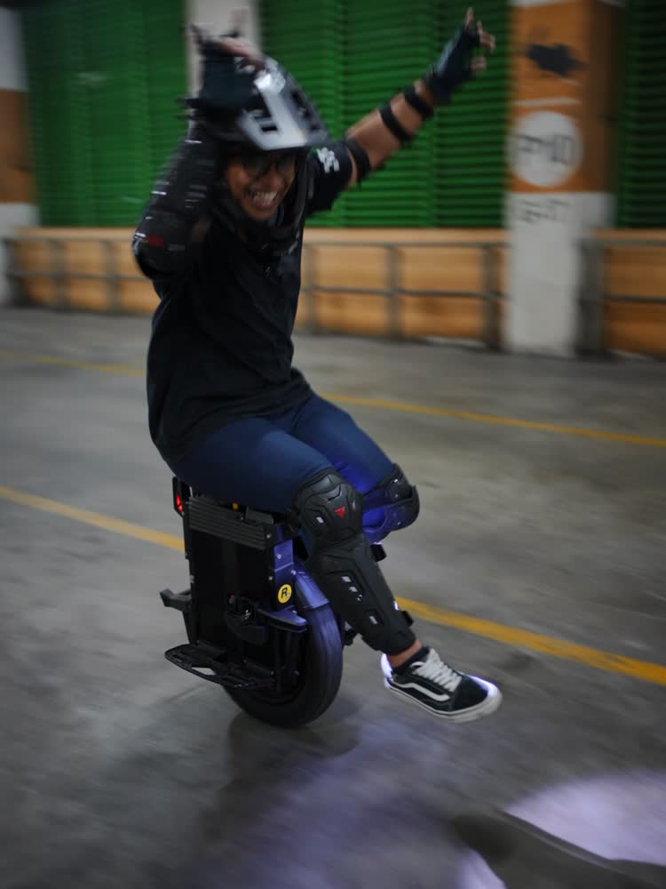 Rider with one arm raised while riding an EUC