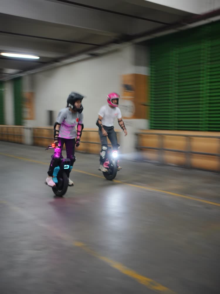 Two riders side by side with pink and teal underglow