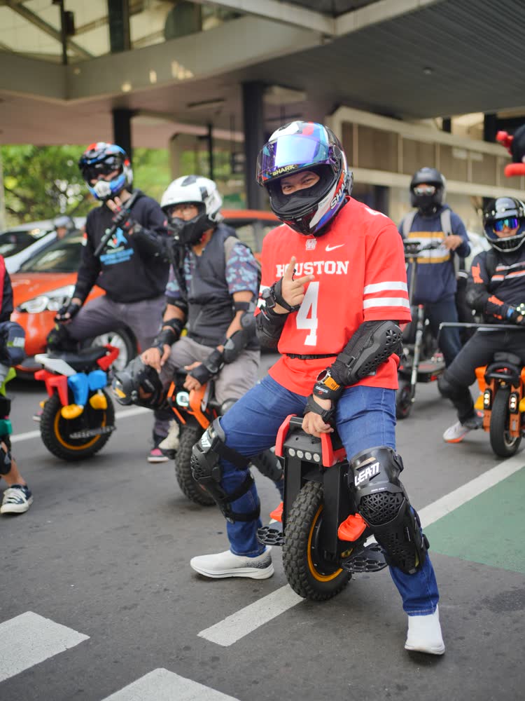 Rider in a red jersey seated on an EUC in traffic