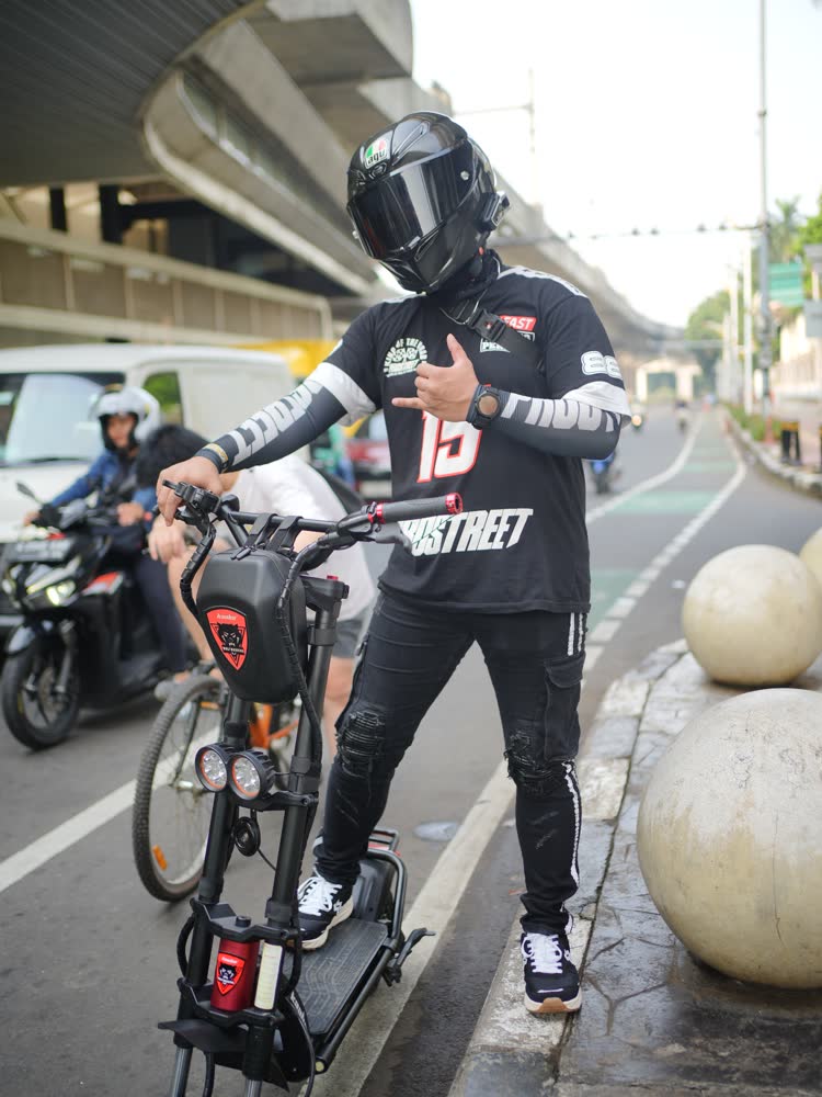 Scooter rider giving a thumbs up beneath a flyover
