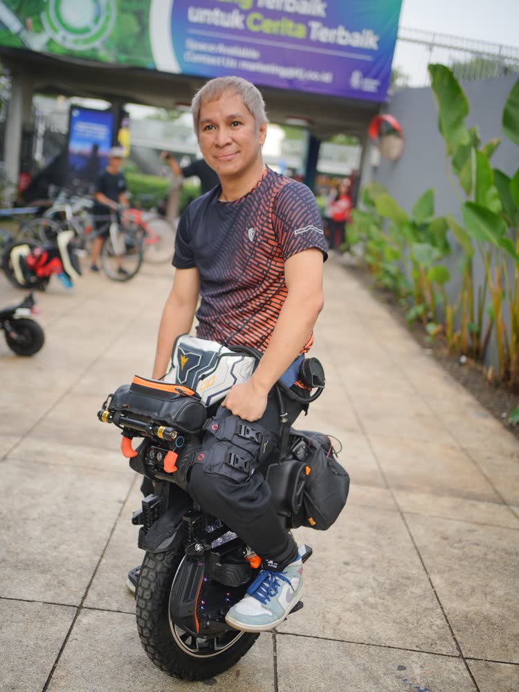 Older rider smiling beside a fully loaded EUC